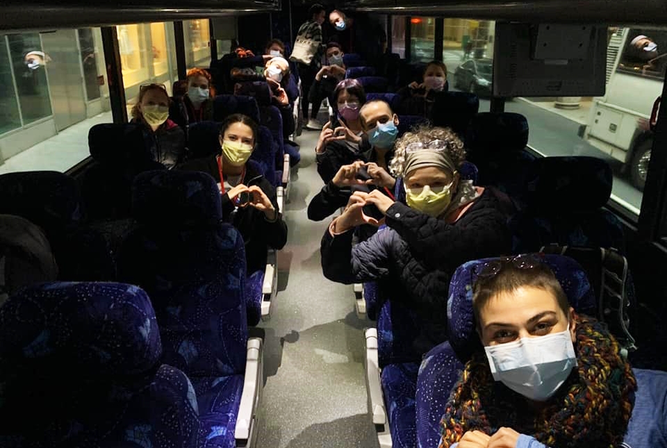 People posing together in a bus wearing protective face masks